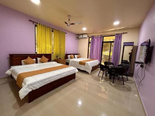 a bedroom with two beds and a table in it at SAHAY VILLA RESORT 