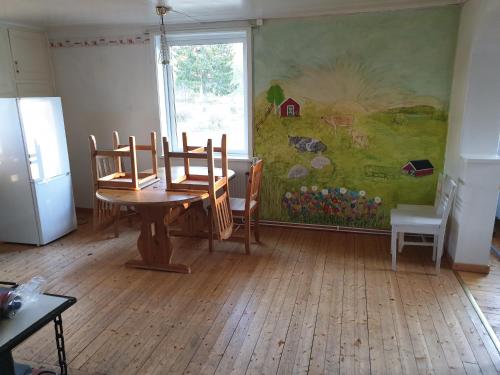 een eetkamer met een tafel en stoelen en een muurschildering bij Större gäststuga 