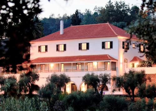 une grande maison blanche avec un toit rouge dans l'établissement Quinta da Palmeira - Country House Retreat & Spa, à Cerdeira