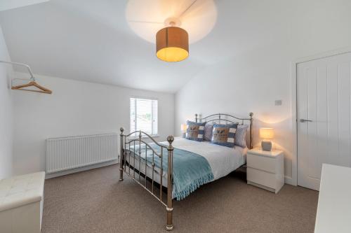 a white bedroom with a bed and a lamp at Sea Breeze Apartment in Walton-on-the-Naze