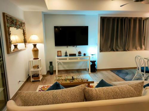 a living room with a couch and a tv at Waterfront Karon Beach by PHR in Karon Beach