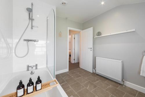 uma casa de banho com uma banheira e um chuveiro com garrafas de vinho em Sea Breeze Apartment em Walton-on-the-Naze
