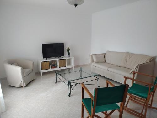a living room with a couch and chairs and a tv at Casa familiar con piscina, cerca de la playa in Ciutadella