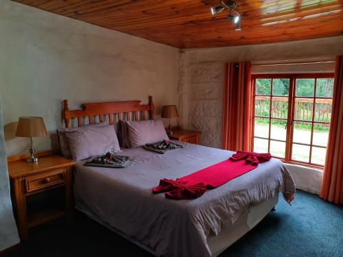 um quarto com uma cama com lençóis vermelhos e uma janela em Gooderson Leisure Mountain View Cottages Self Catering and Timeshare Resort em Drakensberg Garden