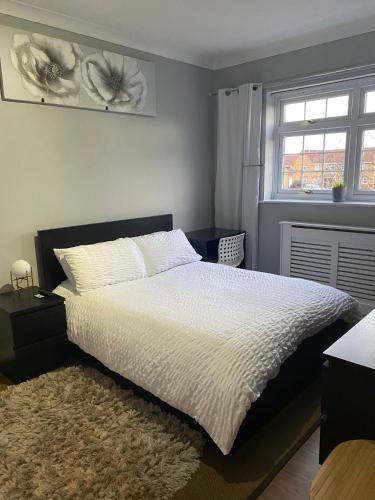 um quarto com uma cama branca com um tapete e uma janela em Thembile House em Thornaby on Tees