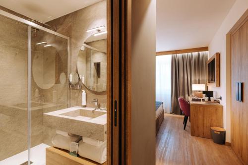 uma casa de banho com um lavatório e uma cabina de duche em vidro. em Valtur Cervinia Cristallo Ski Resort em Breuil-Cervinia
