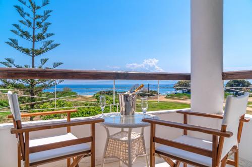 una mesa y sillas en un balcón con vistas al océano en Arco Beach Hotel, en Agia Paraskevi