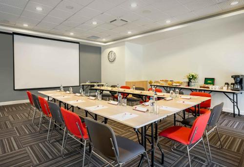 a conference room with tables and chairs and a projection screen at Ibis Izmir Alsancak in Izmir