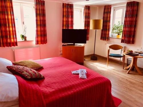 a bedroom with a bed with a red blanket and a television at Hotel Burg Abenberg in Abenberg