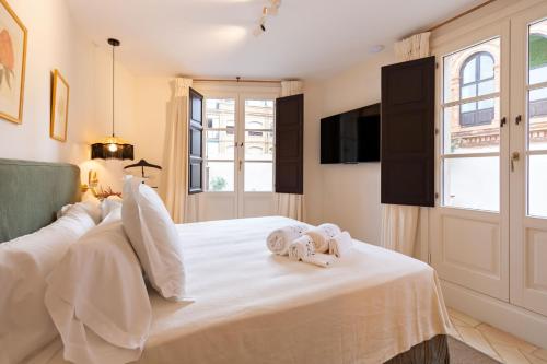 a bedroom with a white bed with towels on it at Real Casa de la Moneda Deluxe Apartments in Seville