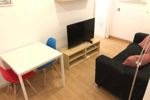 a living room with a television and a table and chairs at NEW! Apartment in Sarria near Metro in Barcelona