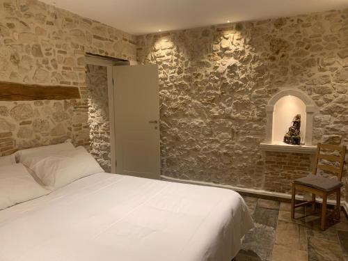 - une chambre avec un lit et un mur en pierre dans l'établissement Le dimore nel borgo, à Pescocostanzo