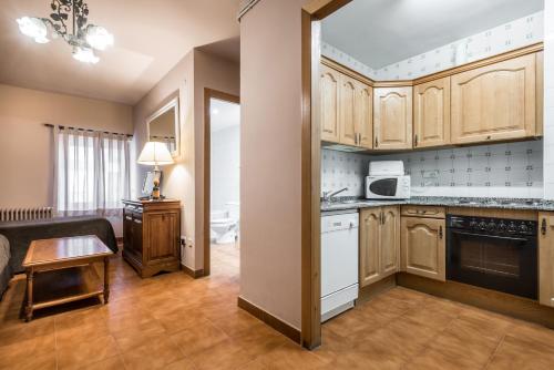 a kitchen with wooden cabinets and a living room at Riu Nere Mountain Apartments in Vielha