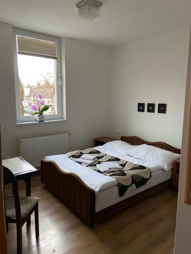 a bedroom with a bed and a window and a chair at Guest House Penzión Fortuna in Tvrdošín