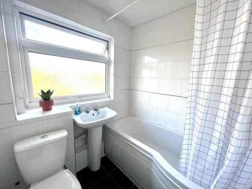 a white bathroom with a toilet and a sink and a window at Three bedroom house, close to airport, A1, NCL in Kenton