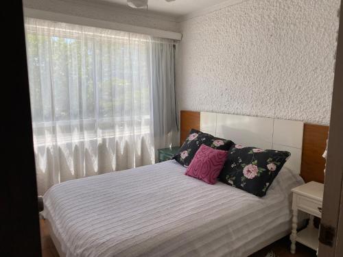 um quarto com uma cama com almofadas e uma janela em Excelente y práctico em Punta del Este