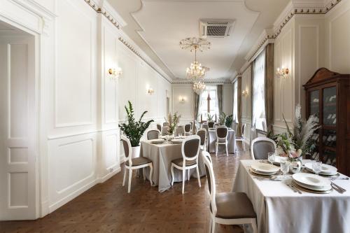 a restaurant with white tables and chairs and a chandelier at Dwór Prezydencki Boutique Hotel & SPA in Tarnów