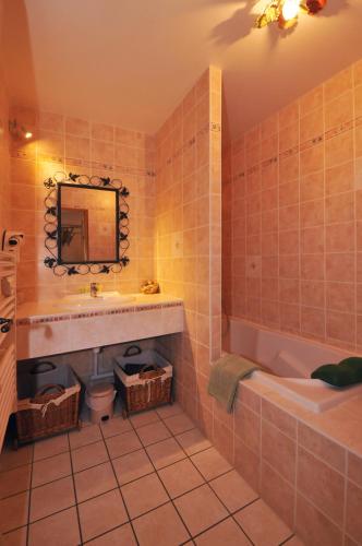 une salle de bain avec un lavabo, une baignoire et un miroir dans l'établissement La Boulonne, à Festigny