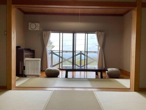 uma sala de estar com uma mesa e uma grande janela em HARUNA SKY Panoramic view of Nasu,private space surrounded by fir trees,relaxing stone bath,watching movies on a 120inch big screen em Nasu