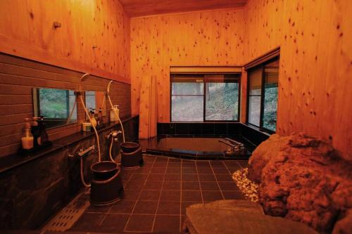 baño grande con bañera y lavamanos en HARUNA SKY Panoramic view of Nasu,private space surrounded by fir trees,relaxing stone bath,watching movies on a 120inch big screen en Nasu