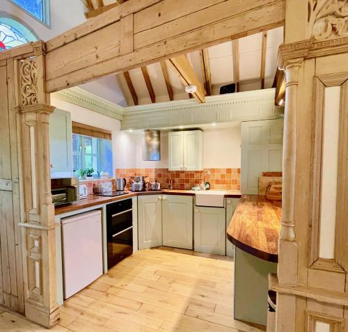 uma grande cozinha com armários brancos e piso em madeira em House on the Brooks Self catering Holiday let South Downs West Sussex Sleeps 14 em Pulborough