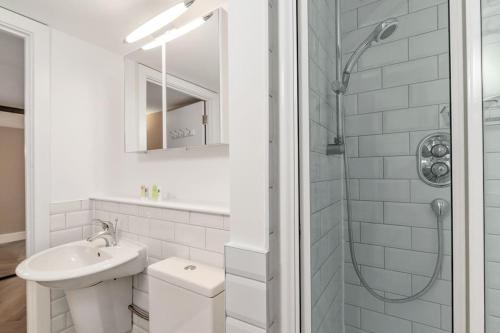a white bathroom with a sink and a shower at GuestReady - Beige barley near museum in London