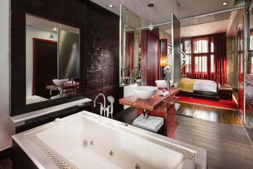 a bathroom with a large tub and a bedroom at Buddha-Bar Hotel Prague in Prague