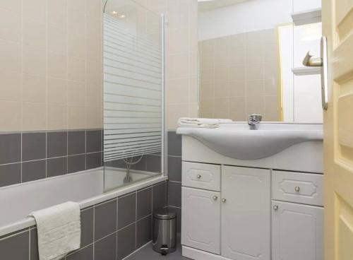 une salle de bain avec un lavabo, un miroir et une baignoire dans l'établissement Le Cocon Bord de mer, à Belgodère