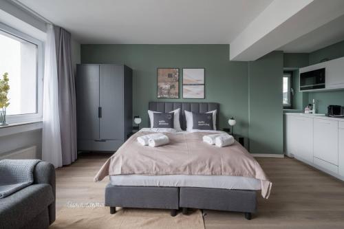 a bedroom with a large bed with green walls at Limehome Saarbrücken Berliner Promenade in Saarbrücken