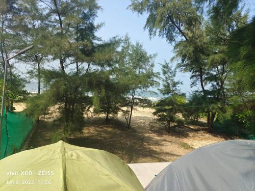 a tent sitting next to a field with trees at His Grace Camping at Malpe Beach in Udupi