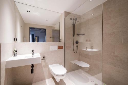 a bathroom with a shower and a toilet and a sink at Limehome Saarbrücken Berliner Promenade in Saarbrücken