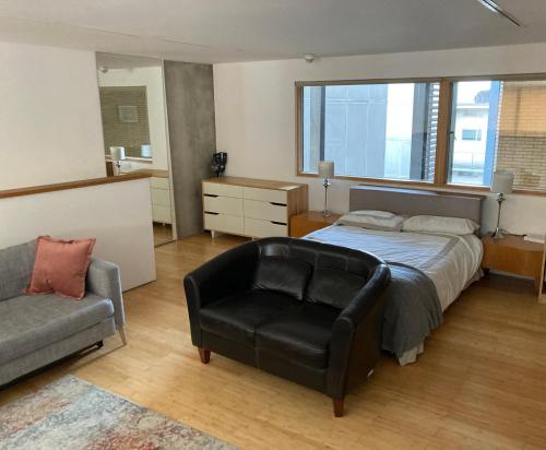 倫敦的住宿－Loft in Haggerston，一间卧室配有一张床、一把椅子和一张沙发