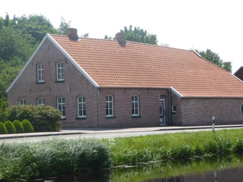a brick building with an orange tile roof at Ferienwohnung Gulf im Gulfhof am Kanal in Großefehn 