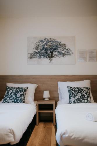 a bedroom with two beds and a tree on the wall at Villa Garden in Oleśnica