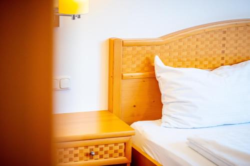 a bed with a wooden headboard and a white pillow at Metzenhof in Kronstorf