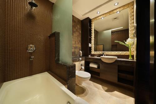 a bathroom with a tub and a toilet and a sink at Park Apartments Dubai, an Edge By Rotana Hotel in Dubai