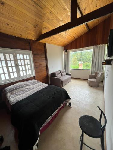 a bedroom with a bed and a chair in a room at Casa de madeira em Lavras Novas in Lavras Novas