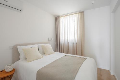a white bedroom with a white bed and a window at Lapa 84-A - seafront house in Póvoa de Varzim