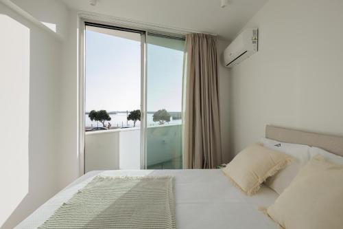 a bedroom with a white bed with a large window at Lapa 84-A - seafront house in Póvoa de Varzim