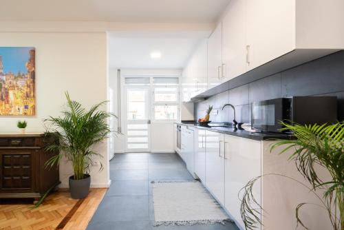 a kitchen with white cabinets and potted plants at Host Wise - Spacious Fresh Flat w Terrace - Near Sea in Espinho