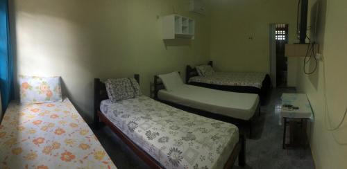 Habitación con 3 camas y mesa con ventana en Novo Hotel en Carolina