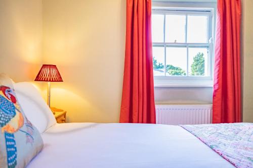 a bedroom with a bed and a window with red curtains at Bragborough Hall Coach House in Braunston