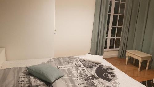 Una cama con una manta y una almohada. en Chambre Ricardo en Orsay