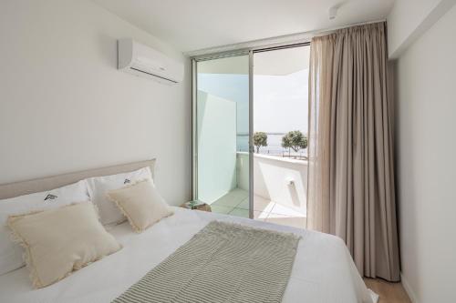 1 dormitorio con cama blanca y balcón en Lapa 84 - seafront house, en Póvoa de Varzim