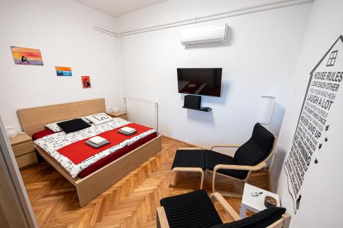 1 Schlafzimmer mit einem Bett und 2 Stühlen sowie einem TV in der Unterkunft That Cat Flat - free parking, near city center, cats! in Ljubljana