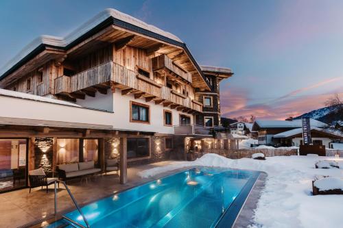 a house with a swimming pool in the snow at Knappensteig Appartements in Wagrain