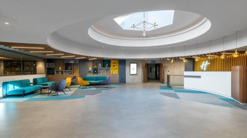 a lobby with blue chairs and a large ceiling at Holiday Inn London Gatwick - Worth, an IHG Hotel in Crawley