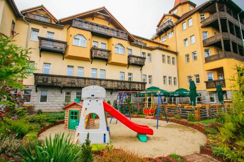 un parco giochi con scivolo di fronte a un edificio di St Lukas Medical & SPA a Świeradów-Zdrój