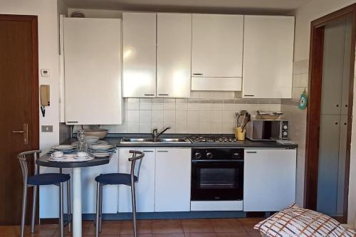 uma cozinha com armários brancos e uma mesa com cadeiras em Casa vacanze Donna Michela em Ponzano Vêneto
