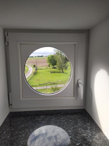 a round window in a room with a view of a field at Gîte Le Framboisier V de la distillerie Bio Spirit Belgium in Neufchâteau